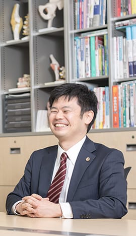 笑顔で座っている弁護士深田先生の写真