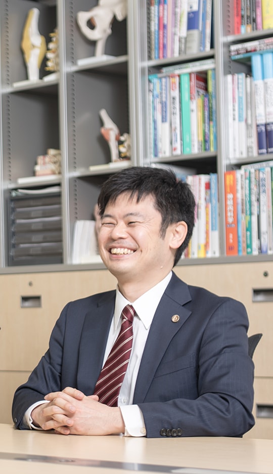 笑顔で座っている弁護士深田先生の写真